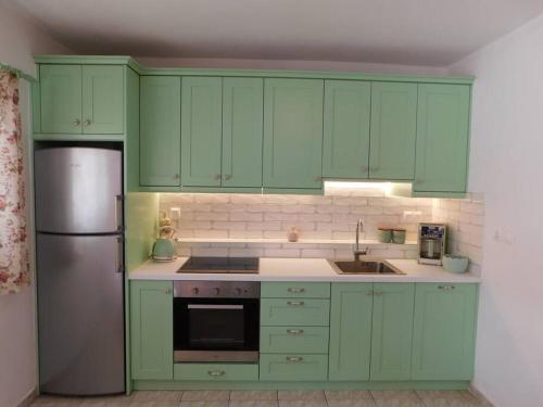 a kitchen with green cabinets and a stainless steel refrigerator at Primavera Apartment in Pilaroú