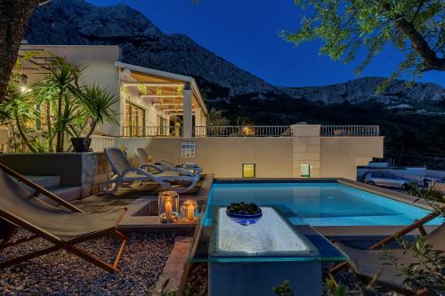 a backyard with a pool and chairs and a house at Villa Rita in Makarska