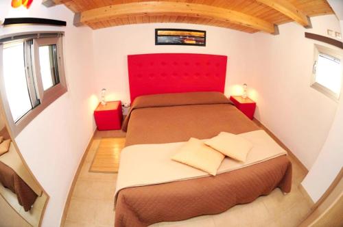 - une chambre avec un grand lit et une tête de lit rouge dans l'établissement One bedroom appartement at Punta Secca 100 m away from the beach with sea view terrace and wifi, à Punta Secca