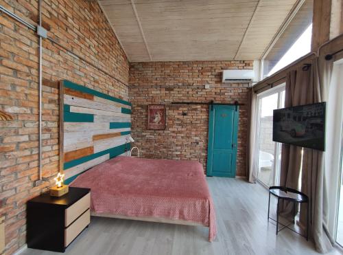 a bedroom with a bed and a brick wall at Время Че in Sukhum