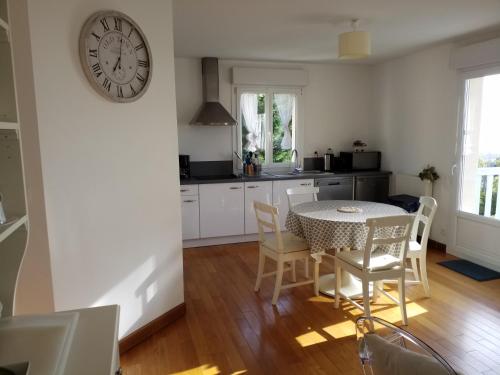 een keuken met een tafel en een klok aan de muur bij Appartements et gîte Les Hauts de Sophia in Trouville-sur-Mer