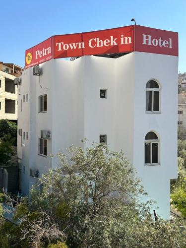 un edificio bianco con un cartello che legge il check-in in città di Petra Town Check-Inn a Wadi Musa