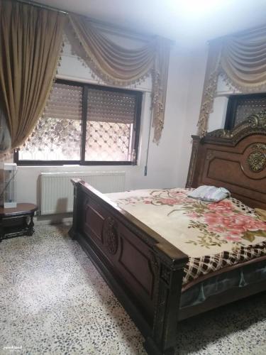 a bedroom with a large wooden bed in front of a window at Duraidi in Amman