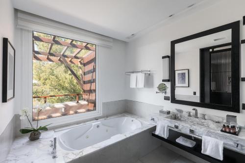 a bathroom with a tub and a large window at Sofitel La Reserva Cardales in Río Luján