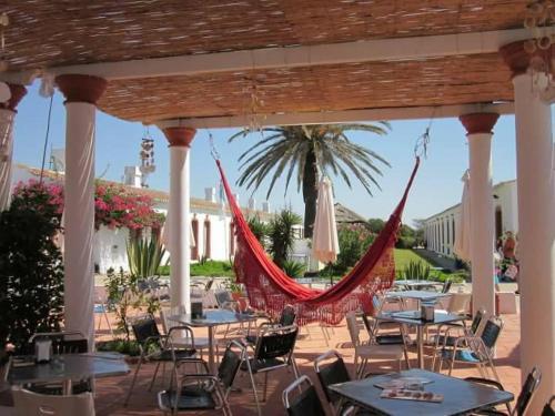 a patio with tables and chairs and a hammock at Pedras D'el Rei - Relax Estúdio in Tavira