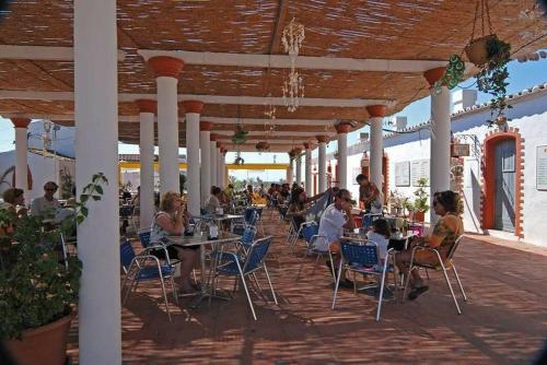 um grupo de pessoas sentadas em mesas num pátio em Pedras D'el Rei - Relax Estúdio em Tavira