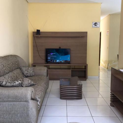 Hospedagem Petrolina في بترولينا: غرفة معيشة مع أريكة وتلفزيون بشاشة مسطحة