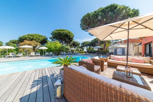 a pool with furniture and an umbrella next to a swimming pool at Les Capucines Saint Tropez in Saint-Tropez