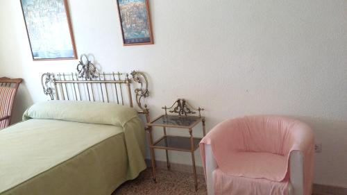 a bedroom with a bed and a pink chair at 2 bedrooms apartement with sea view shared pool and furnished balcony at Aguilas in Águilas
