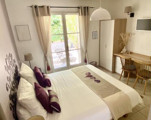 une chambre avec un grand lit blanc avec une fenêtre dans l'établissement Le Jardin de Lau, à Aubignan