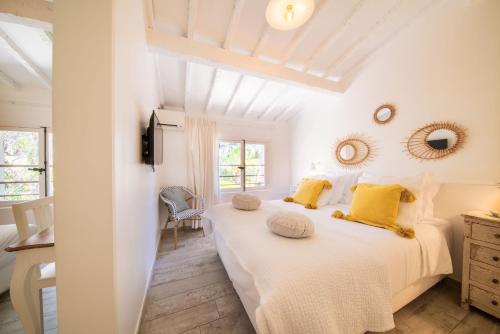 um quarto branco com 2 camas e almofadas amarelas em Les Capucines Saint Tropez em Saint-Tropez