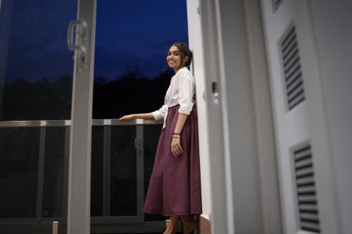 a woman standing on a balcony looking out of a window at Bella Casa in Vagamon