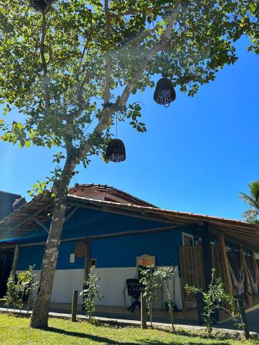 a blue house with baskets hanging from a tree at Céu Azul Pousada in Arraial d'Ajuda