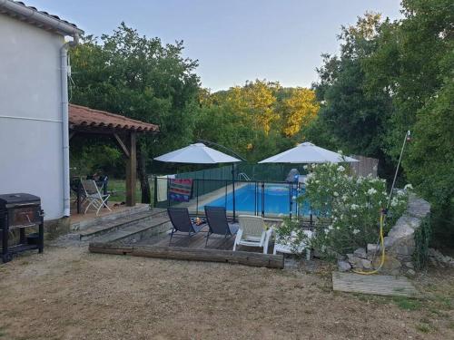 une cour arrière avec une piscine avec deux chaises et des parasols dans l'établissement Maison avec piscine au cœur des Gorges de l'Ardèche, à Balazuc