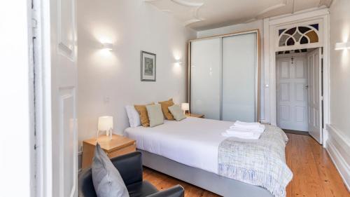 1 dormitorio blanco con 1 cama y 1 silla en Porto 61 - Bright 2BR w/ Balcony by LovelyStay, en Oporto