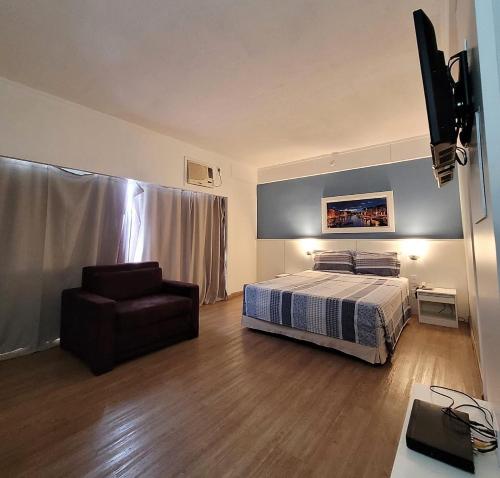 a hotel room with a bed and a chair at Flat R Borges Lagoa Ibirapuera c/ garagem UH1005 in Sao Paulo