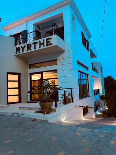a white building with a sign that reads myrite at Myrthe Apartments in Myrtos