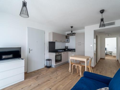 un salon avec un canapé bleu et une table dans l'établissement Appartement Neuf 3* à Mimizan - 100m de l'Océan, Piscine, Clim, WiFi, 4 Pers, Ménage inclus - FR-1-50-112, à Mimizan