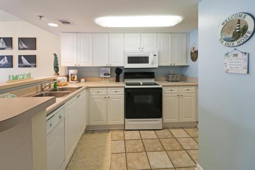 a kitchen with white cabinets and a black stove top oven at Tybee Summer Winds 523 Condo in Tybee Island