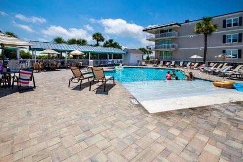 a swimming pool with chairs and people in a hotel at Tybee Summer Winds 523 Condo in Tybee Island