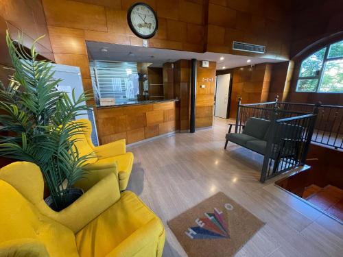 sala de estar con sofá amarillo y reloj en AZ Orús Factory Hotel - Parking Gratuíto, en Zaragoza