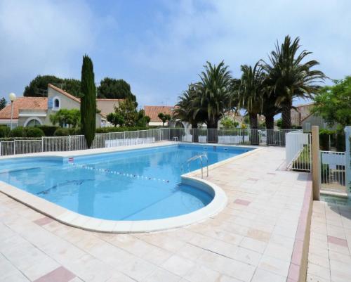 - une grande piscine dans une cour bordée de palmiers dans l'établissement maison Valras Plage - Résidence Lou Portalou, à Valras-Plage
