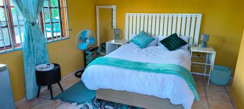 a bedroom with a bed with white sheets and green pillows at The Homestead Richardsbay in Richards Bay