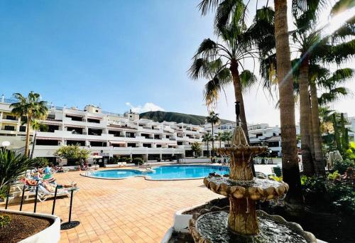 a fountain in front of a hotel with palm trees at Comfy home with large terrace five minutes from ocean in Los Cristianos