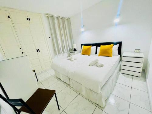 a white bedroom with a large bed with yellow pillows at Comfy home with large terrace five minutes from ocean in Los Cristianos