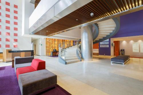 a lobby with a staircase and a red chair at Camino Real Pedregal Mexico in Mexico City