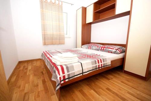 een slaapkamer met een bed en een houten vloer bij Cosy Apartment in Žrnovo - 30 sqm with Shared Pool in Korčula