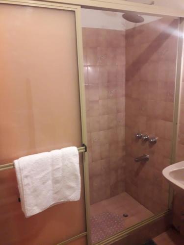a shower with a glass door next to a sink at D' Charrúas Hostel Concordia in Concordia