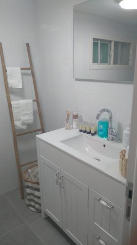 Baño blanco con lavabo y escalera en LTD Hadas Garden apartment en Tiberias