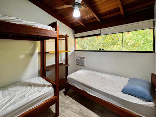 a bedroom with two bunk beds and a window at Casa a 3 min andando da Praia de Paúba com WIFI top in São Sebastião