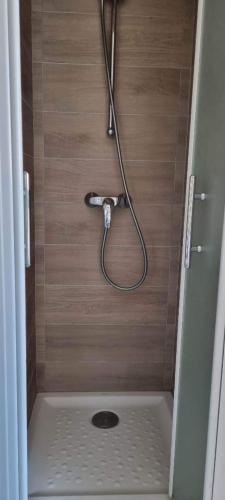 une douche avec un tuyau fixé à un mur en bois dans l'établissement Appartement la méridienne Le Lavandou 2 à 4 personnes, au Lavandou