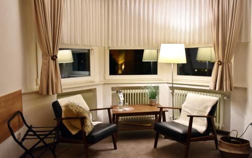 a living room with a table and chairs and windows at Hotel Wappenhof in Braunlage