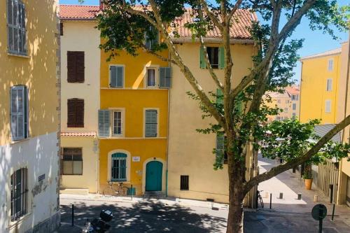 a yellow building with a blue door next to a tree at Logement avec deux velos in Hyères