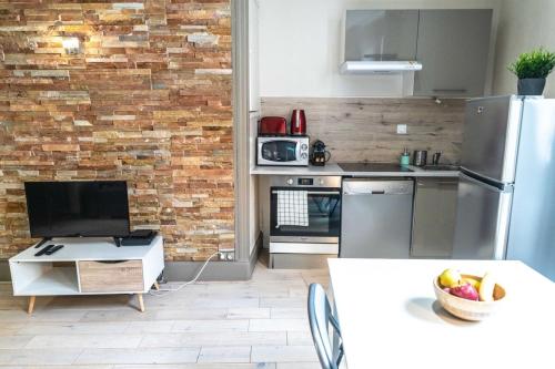 Le NewYorkais - Appartement 4 pers- Oullins-Lyon في أولينز: مطبخ مع ثلاجة ستيل ستانلس وجدار من الطوب