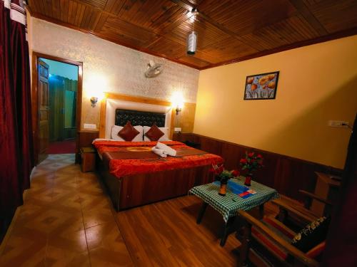 a bedroom with a bed and a table in it at Chetna hotel & cottage in Manāli