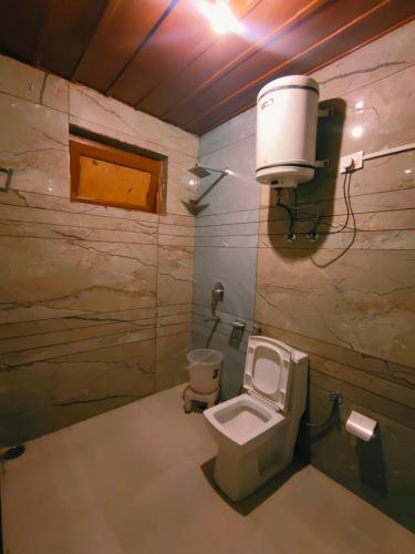 a bathroom with a toilet and a light on the wall at Chetna hotel & cottage in Manāli