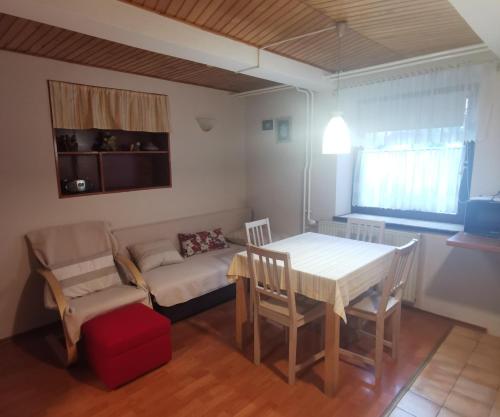 - un salon avec une table, des chaises et un canapé dans l'établissement Apartment Sopar, à Škofja Loka