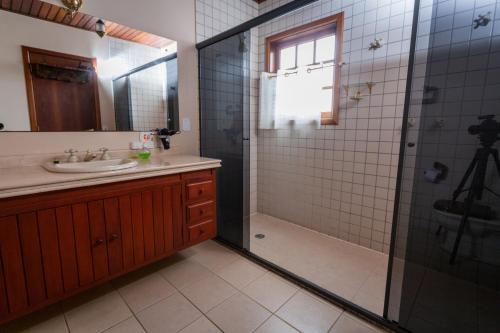 a bathroom with a sink and a shower with a glass door at Guest House Família in Campos do Jordão