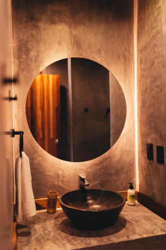a bathroom with a sink with a large mirror at Naked Hotel Zipolite -Adults Only- in Zipolite