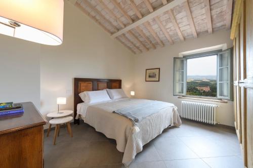 a bedroom with a bed and a desk and a window at Albergo Diffuso Borgo Santo in Asciano