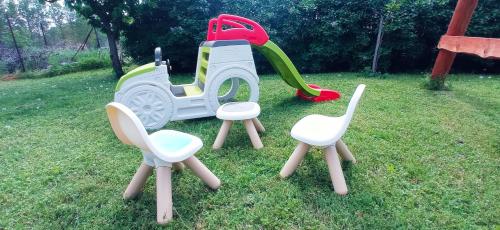 four chairs and a play set in the grass at Robitel Wellness Vendégház Veszprém-Gyulafirátót in Veszprém