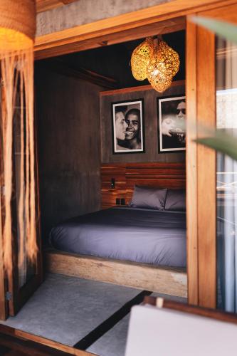 a bed in a room with pictures on the wall at Naked Hotel Zipolite -Adults Only- in Zipolite