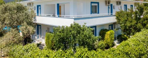 a large white building with blue windows and trees at Studios Suzanna in Potos