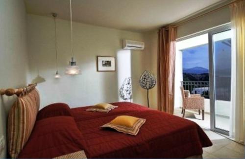 a bedroom with a red bed and a large window at Istron Collection Villas in Istron