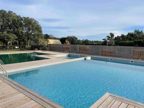 a large swimming pool with a wooden deck at Appartement T2 cosy à San ciprianu in Lecci