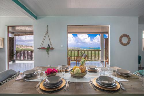 ein Esszimmer mit einem Tisch und Meerblick in der Unterkunft Haut de villa au François in Le François